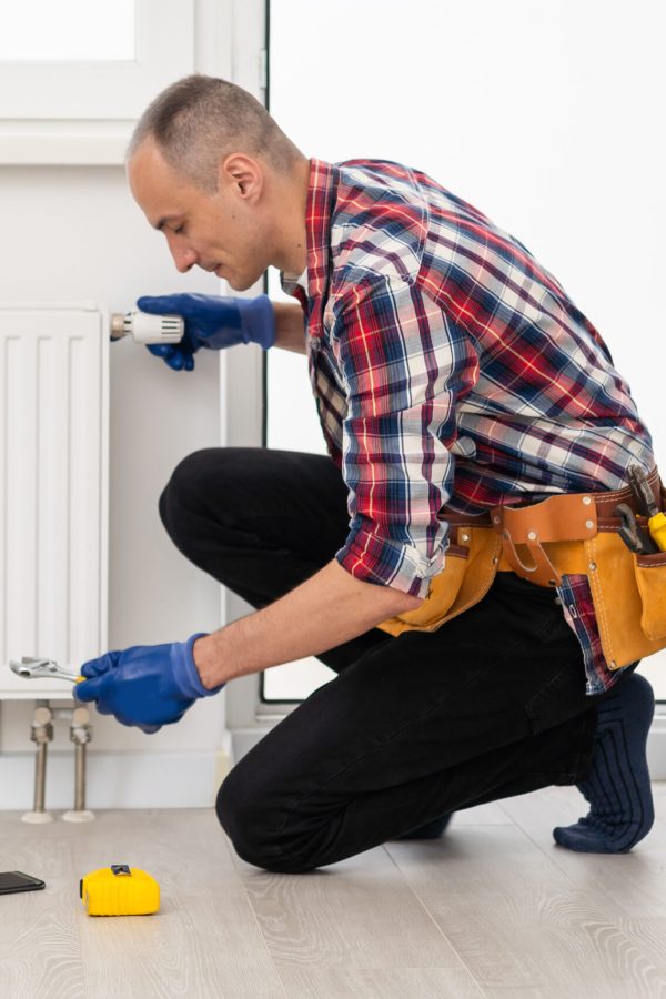 Close-up Of A Young Male Plumber Installing Radiator With Screwdriver. High quality photo