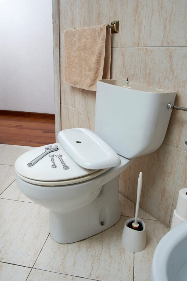 Plumber tools on broken toilet bowl in bathroom.